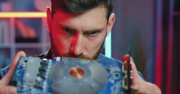 Portrait of good-looking serious confident experienced bearded service worker which considering computer panel in his hands before repairing at home — Stock Video