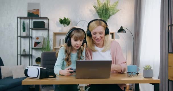 Jolie fille de 12 ans faisant face bouleversé en jouant à des jeux vidéo avec sa belle mère joyeuse qui gagne et célèbre la victoire avec les mains en l'air, concept de loisirs en famille — Video