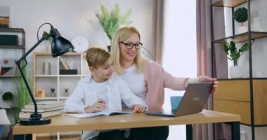 35 yaşında, gözlüklü, gülümseyen mutlu bir anne okul sınavının sonuçlarını kontrol ederken aynı zamanda ergen oğlunun bu görevi üstlenmesi ve dizüstü bilgisayarında görülen sonuçlardan keyif alması.