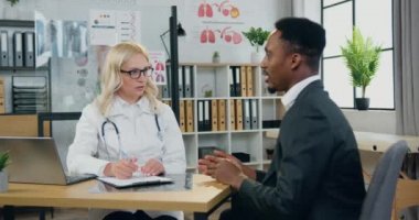 Yakışıklı, şık, Afro-Amerikan üzgün adam profesyonel yetenekli bayan doktoru ziyaret ediyor ve kendini iyi hissetmediğinden ve rahatsız edici semptomlardan yakınıyor.