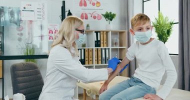 Tıp konsepti. Tıp merkezindeki aşı randevusu sırasında erkeklerin koluna iğne batıran güzel, şefkatli sarışın kadın-doktor.