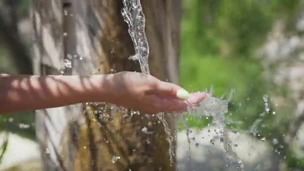 Friss ivóvíz árad a női kézbe. Tiszta víz fröccsenés a női kézre, ökológia koncepció — Stock videók