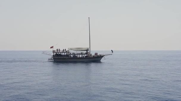 İnsanlarla dolu ahşap gemi, Türkiye kıyıları yakınlarındaki sakin deniz suyunda yelken açıyor. Doğa, açık hava. — Stok video