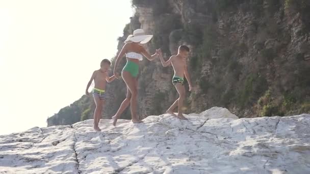 Mulher feliz com dois filhos caminhando juntos na praia ao pôr do sol, ilha férias em família — Vídeo de Stock