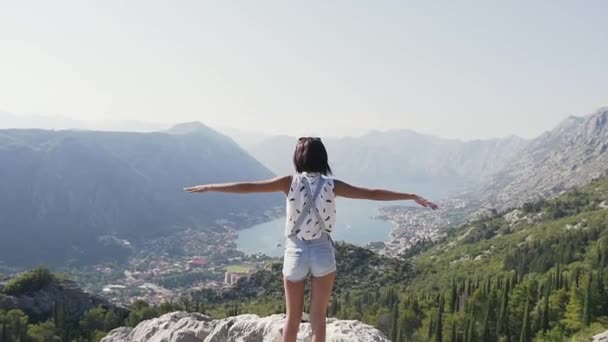 Rückansicht der schönen schlanken Frau beim Erreichen des Ziels oben mit Blick auf den Berg über dem Meer vor blauem Himmel — Stockvideo