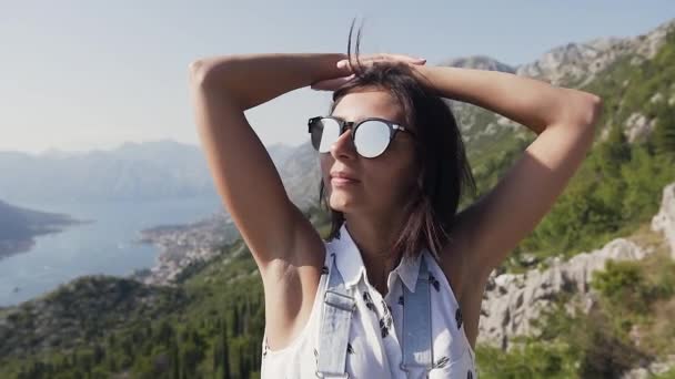 Закінчується розслабленням прекрасної молодої жінки в сонцезахисних окулярах підняті руки на вершині гори з прекрасним Адріатичним морським видом. — стокове відео