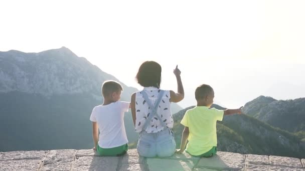 快乐的母亲带着两个孩子在山上，俯瞰高山美景。家庭假期生活方式. — 图库视频影像