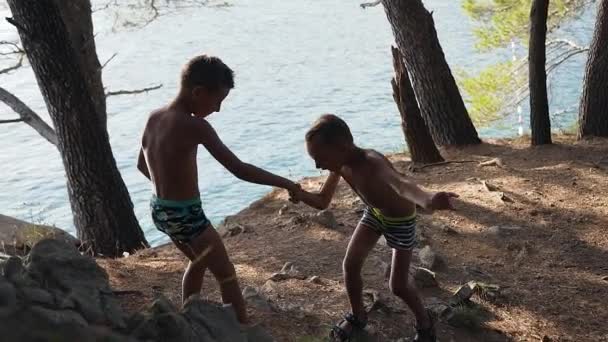 愛らしい男の子8歳は、弟がアドリア海の近くで夏休み中にパスに登るのを助けます — ストック動画