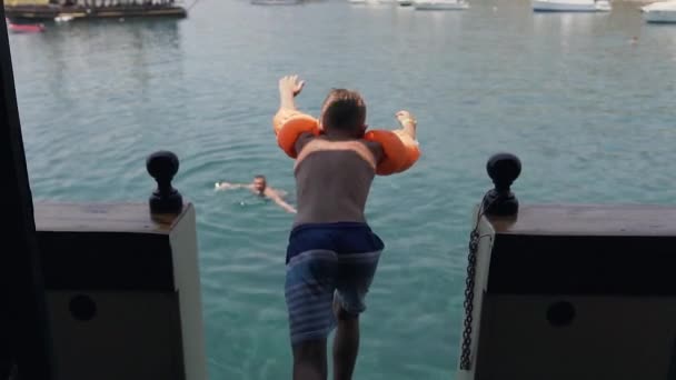 Petit garçon qui saute une fois dans la belle mer bleue pendant les vacances d'été — Video