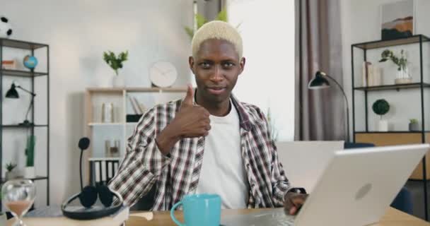 Konsep komunitas LGBT di mana positif percaya diri muda african american gay dengan rambut pirang dan ekspresi wajah spesifik yang melihat ke kamera gesturing jempol ke atas — Stok Video