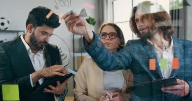 Modern ofiste yeni bir başlangıç projesi için üç dâhice genç profesyonelin ofisinde çalışıyorum. Cam duvarlarda ve yapışkan notlarda hatırlatıcılar var.