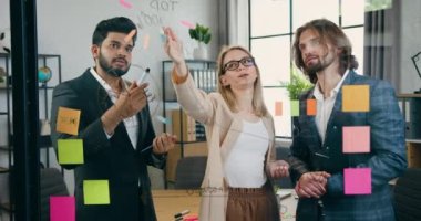 Sempatik, yaratıcı deneyimli ekip, yeni proje üzerinde ortak çalışmanın sonuçlarından ve ofisteki cam duvardaki çizimlere bakarak el çırpmaktan memnun.