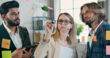 Modern ofisteki cam duvarlarda plaklar kullanarak projeye başlamak için yeni fikirler üreten iyi görünümlü, kendine güvenen yaratıcı erkek ve kadın takımını kapatın.