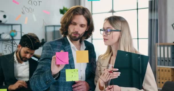 Concept de travail de bureau où belle équipe créative positive réussie remue-méninges nouvelles idées et les enregistrer sur des notes collantes attachées au mur de verre — Video