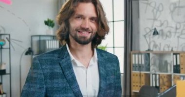 Yakışıklı, gülümseyen, kayak yapan, sakallı, ofis çalışanı cam panonun arkasında poz veren ve sembolü modern ofiste iyi gösteren biri. Kapatın.