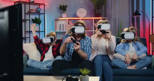 Virtuele entertainment concept waar goed uitziende opgewonden glimlach vrolijke speelse familie videogames spelen in augmented reality bril en het vieren van de overwinning thuis in de avond — Stockvideo