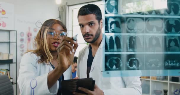 Attrayant confiant intelligent mixte race masculine et féminine travailleurs médicaux debout près de la paroi de verre dans le bureau médical et discuter formule moléculaire qui femme a écrit sur ce mur — Video