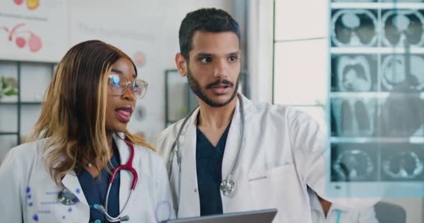 Medicína koncept, kde atraktivní profesionální kvalifikované smíšené rasy lékaři diskutovat o výsledcích rentgenového snímku a zadávání důležitých poznámek do notebooku, zpomalení — Stock video