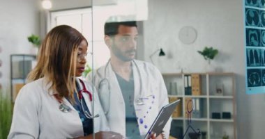 Güzel, kendine güvenen profesyonel kadın doktor ve yetenekli sakallı erkek meslektaşı röntgen sonuçlarına uygun olarak hastanın doğru teşhisi konusunda danışmanlık yapıyorlar.