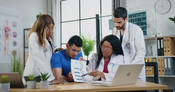 Concepto de trabajo en equipo médico donde experimentaron exitosos doctores inteligentes diversos celebrando una reunión de video vía computadora en la sala médica y explicando los resultados de los infográficos de ADN. — Vídeo de stock