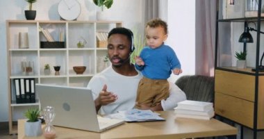 İyi görünümlü, kendine güvenen, kulaklıklı, yüksek yetenekli, siyah derili bir baba. Evde çalışırken iş arkadaşlarıyla görüntülü konuşma yapıyor. Çünkü küçük oğluyla kalması gerekiyormuş.