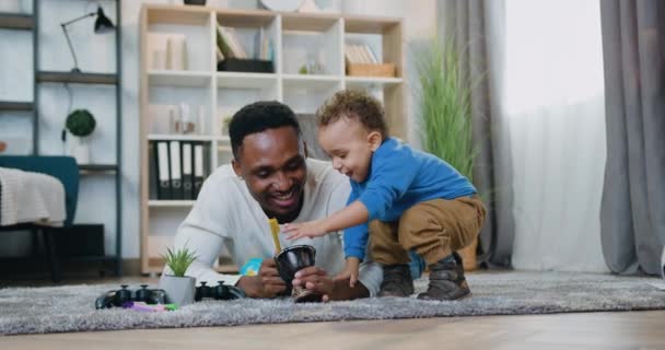 Adorable happy smiling caring african american having fun together with his cute baby boy when they together playing on small drum,fatherhood and child care concept — Stock Video