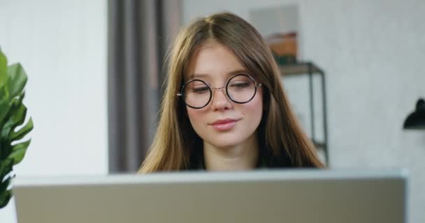 Workflow-Konzept, bei dem attraktive selbstbewusste, positive junge Facharbeiterinnen mit Brille tagsüber zu Hause am Laptop arbeiten, Frontansicht — Stockvideo
