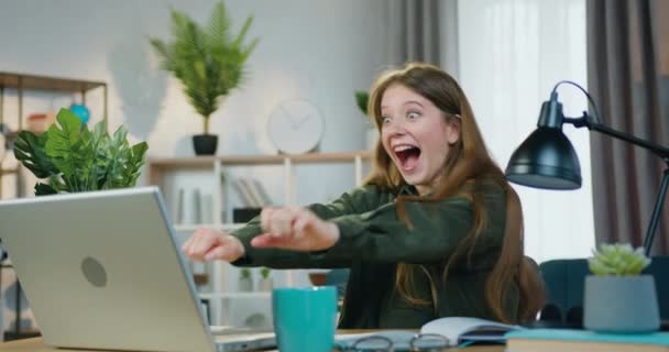 Schöne überraschte glückliche 25-jährige Mädchen, die emotional auf fantastische Nachrichten auf dem Laptop-Bildschirm reagiert und Tanzbewegungen macht, die Glück und Freude fühlen — Stockvideo
