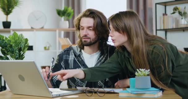 Atraente confiante casal jovem altamente qualificado de freelancers discutindo detalhes do projeto de arranque conjunto visualização de informações sobre laptop em casa, conceito de sucesso — Vídeo de Stock