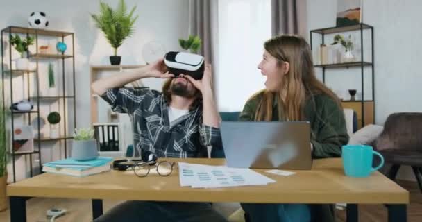 Acelerar el rodaje de la cámara en una pareja inteligente alegre y despreocupada que disfruta del entretenimiento de realidad virtual en gafas 3D especiales en casa — Vídeo de stock