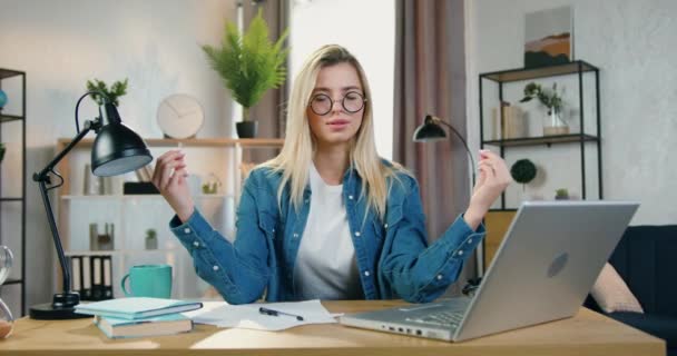 Çekici, kendinden emin, gözlüklü genç sarışın kadın ev bilgisayarında, iş akışında ve gevşeme konseptinde meditasyon yapıyor. — Stok video