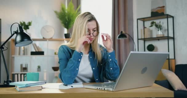Güzel, yorgun, çalışkan genç bir kadın bilgisayarda yazı yazıyor. Sonra da baş ağrısı ve iş akışı konseptini hafifletmek için gözlüğünü masaj tapınaklarına çıkarıyor. — Stok video