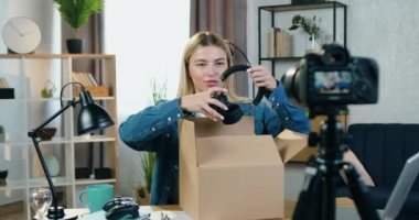 Çekici, mutlu, mutlu, sarışın blog yazarı. Kameraya paketleri açıyor, yeni kulaklıkları çıkarıyor ve takipçiler için video günlüğü kaydederken bunları kafasında gösteriyor.