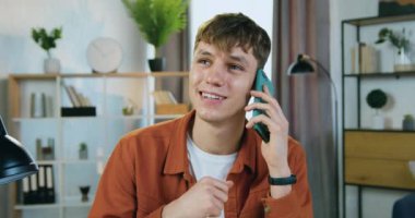 Çekici, güler yüzlü genç sarışın adam arka planda güzel dekore edilmiş oda, ön manzara, yavaş çekim