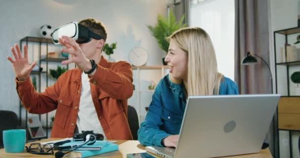 Przystojny pozytywny nowoczesny młody facet w specjalne okulary 3D oglądanie futurystyczny wizja który został wybrany dla niego przez jego dziewczyna na komputerze, czas wolny koncepcja — Wideo stockowe