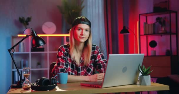Close up of good-looking confident relaxed young blond woman in casual clothes which sitting in front of camera at her home workplace in the evening — Stock Video