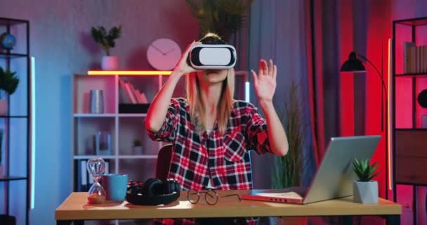 Sympatický jistý chytrý moderní mladá blondýna dívka ve speciálních 3D brýle pracuje na virtuální displej sedí na svém pracovišti doma ve večerních hodinách, zpomalení — Stock video