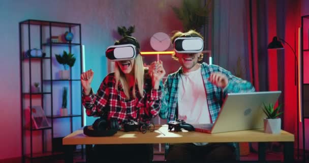 Attrayant heureux rire jeune couple moderne s'amuser ensemble dans des casques de réalité virtuelle passer des loisirs communs à la maison le soir, concept de technologie moderne — Video