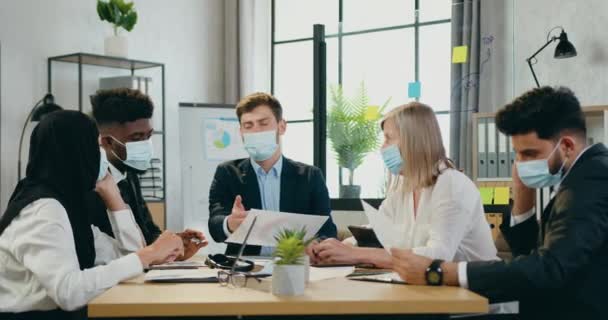 Jóképű tapasztalt vezérigazgató védő maszk gazdaság üzleti találkozó az ő magabiztos különböző korú vegyes faj beosztottak védő maszkok is, irodai munka során pandémia covid-19 — Stock videók