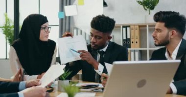 Yakışıklı, siyah tenli adam ofis odasında toplantı sırasında diğer ortaklara ve çevrimiçi ortaklara mali raporları açıklıyor.