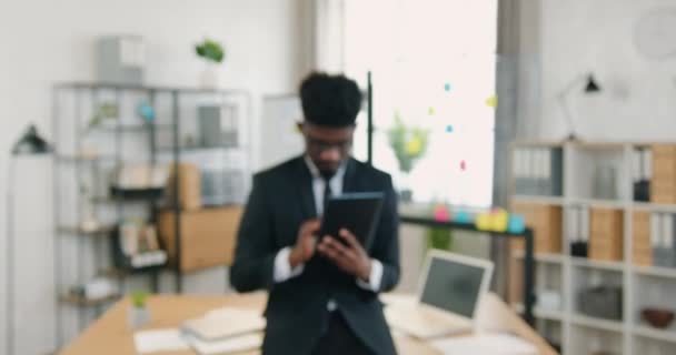 Camera schieten op aantrekkelijke glimlachende moderne zelfverzekerde ervaren bebaarde zwart-gevilde office manager die op zoek op de camera in prachtig versierd kantoor — Stockvideo