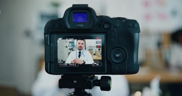 Blick durch die Kamera auf einen attraktiven, erfolgreichen, bärtigen Arzt, der sein medizinisches Vlog in einer eigenen Arztpraxis für das Internet-Publikum aufzeichnet — Stockvideo