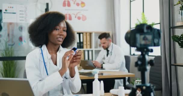 Концепция медицины, где привлекательный позитивный уверенный в себе высококвалифицированный 30-летний африканский врач женщина-врач объясняет на камеру для онлайн-аудитории, как использовать электронный пульсометр — стоковое видео
