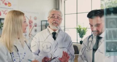 Çekici, yetenekli, sakallı bir doktor. Cam duvarın yanında başarılı erkek ve bayan meslektaşlarıyla konuşuyor. Röntgen sonuçlarıyla birlikte.