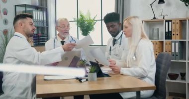 Klinikte çalışmak. İyi görünümlü, kendine güveni tam, sakallı, olgun bir doktorun klinikte profesyonel melez ırkla toplantı yaptığı bir yer.