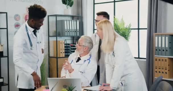 Medicína koncept, kde atraktivní pozitivní úspěšný zkušený zdravotníci v uniformách mluvit se svým respektovaným kvalifikovaným vousatý lékař během společného setkání na klinice — Stock video