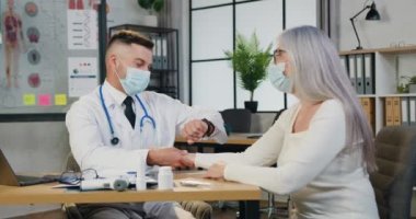 Tıbbi merkezde randevu. Yüz maskesi takmış, kendine güvenen erkek doktor kadın hastaların bileklerindeki nabzını ölçüyor. El saatine bakıyor ve ritmi sayıyor.