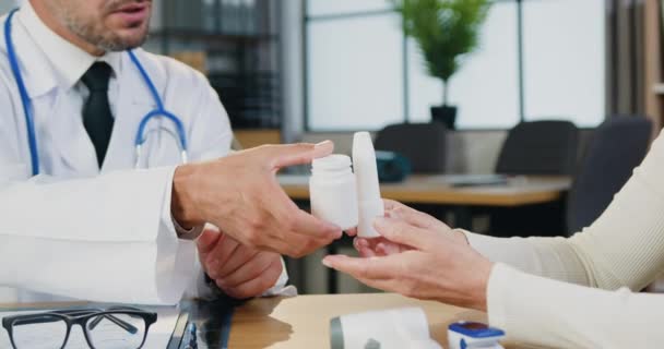 Unbekannter bärtiger Arzt gibt Patientin während ihres Besuchs im Klinikzentrum Medikamente, Frontansicht — Stockvideo