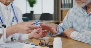 Sakallı hastadaki oksijen seviyesini kliniğe ziyaretinde pusle oximeter kullanarak ölçen kimliği belirsiz profesyonel kadın doktoru kapatın.