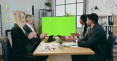 Çekici tatmin edici, başarılı, yüksek vasıflı, melez iş adamları modern konferans odasında TV yeşil ekranında sunulmadan önce el çırpıyorlar.